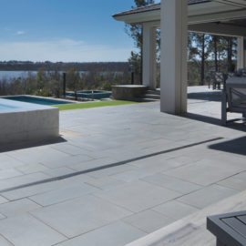 Platinum Premiastone pool deck with large format natural stone pavers surrounding a modern swimming pool.